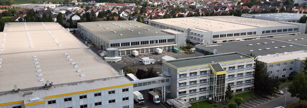 Luftaufnahme eines Industriegebiets mit verschiedenen Lager- und Produktionshallen sowie Bürogebäuden.